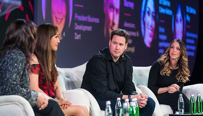A panel discussion at an event featuring BecomingX, with speakers seated on stage in conversation.